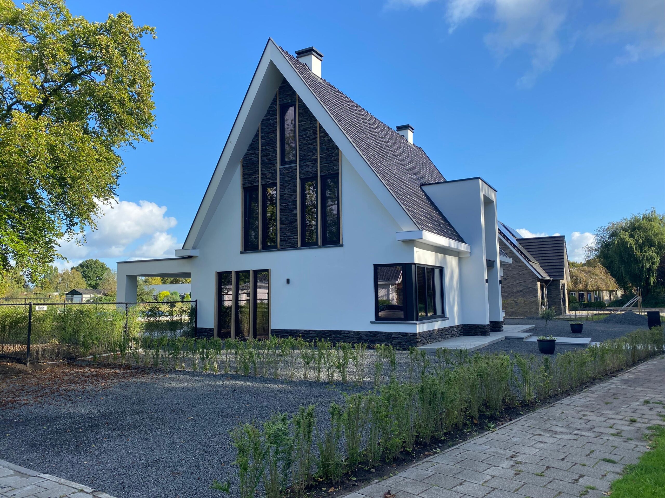 Landelijk-moderne woning met uitkragende kap wat  een beeldbepalend element vormt dat de gevel beschermt en de architectonische uitstraling versterkt